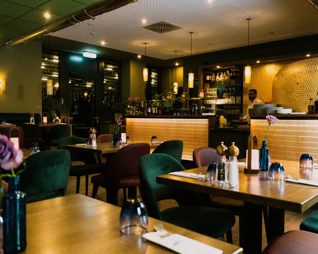 Gedeckte Tische im warm beleuchteten Gastraum der Osteria Siros