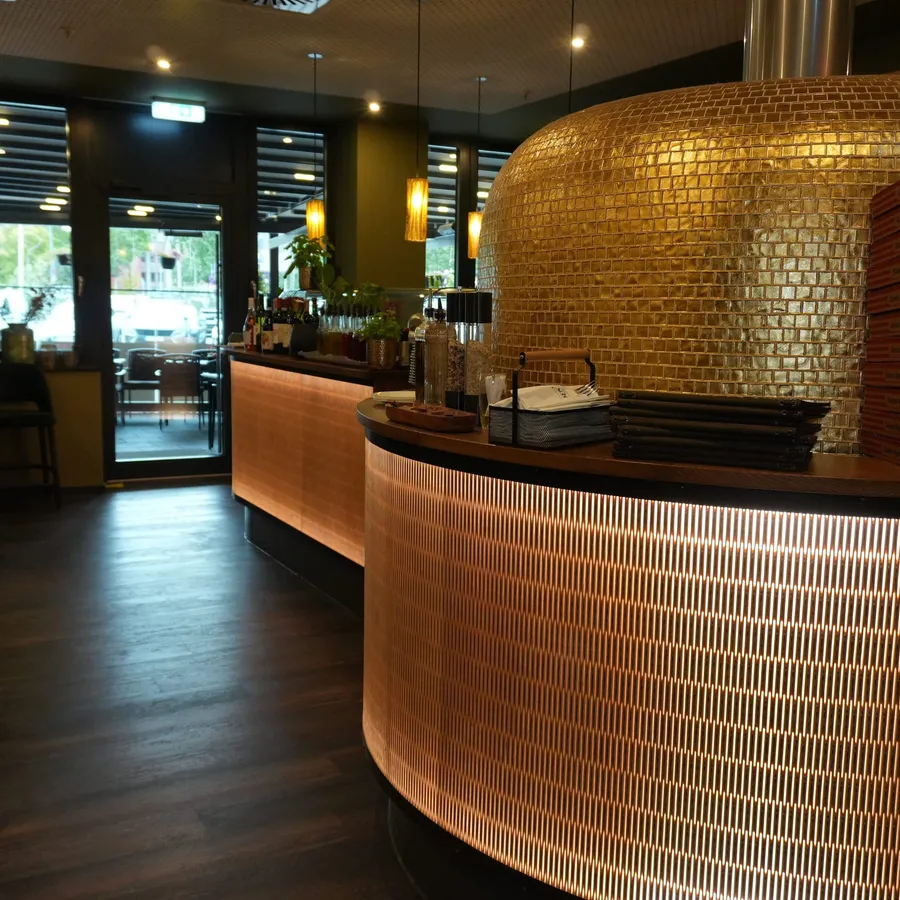 Geschwungene Bar vor dem goldenen Pizzaofen