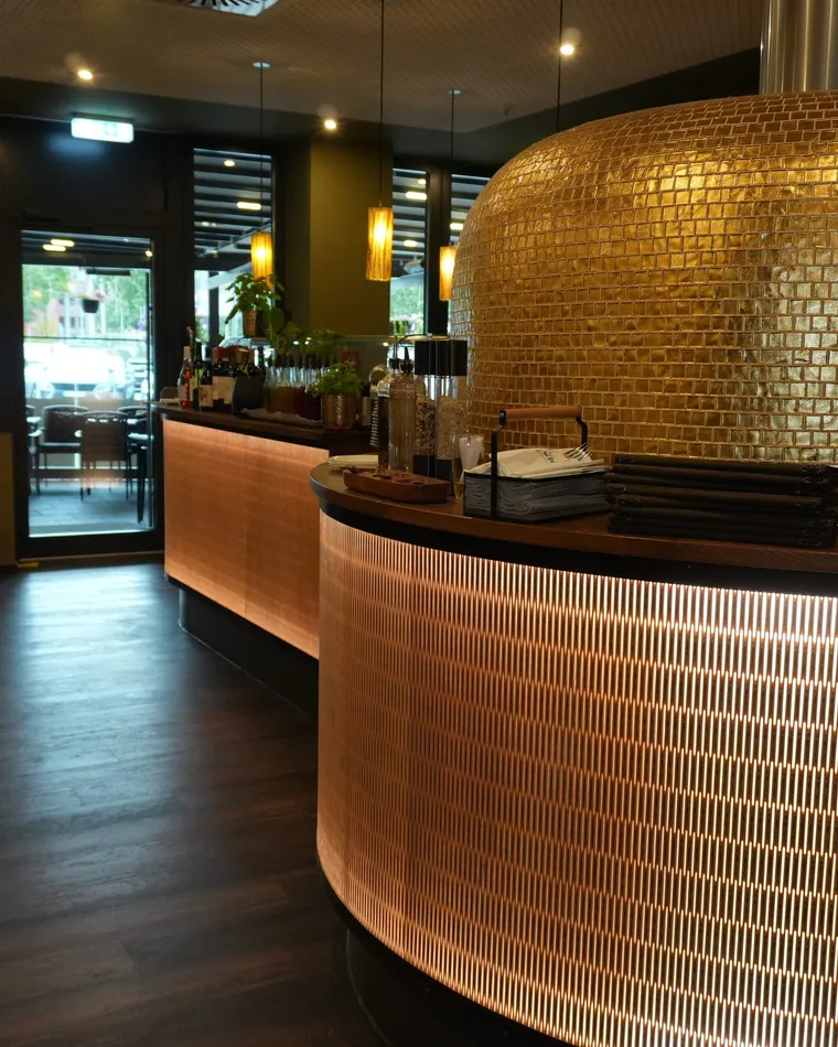 Geschwungene Bar und goldener Pizzaofen