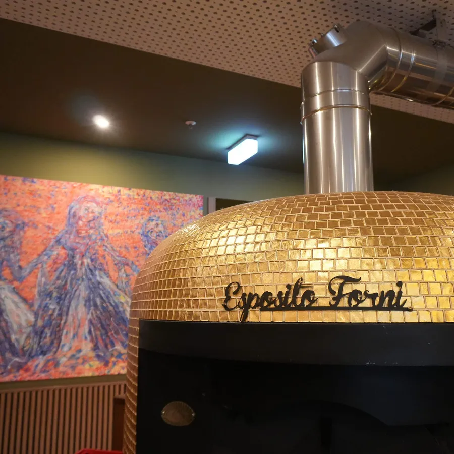 Goldener Pizzaofen vor farbiger Kunst