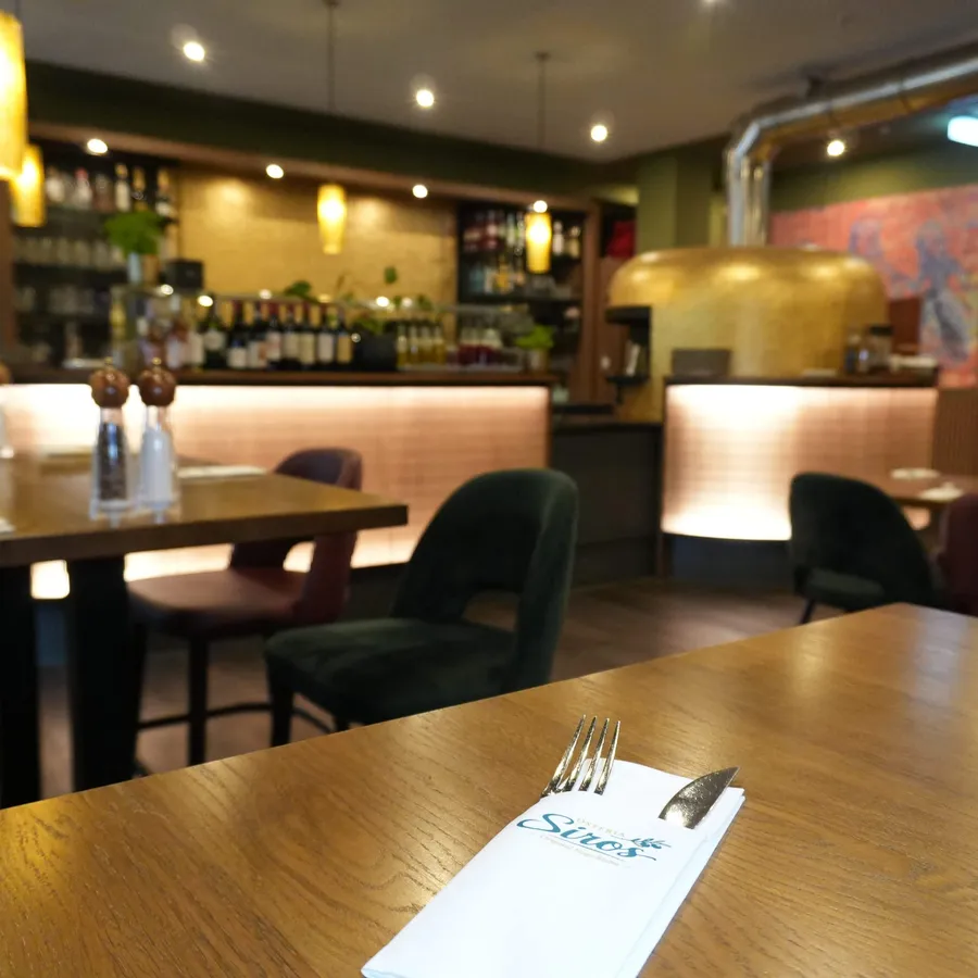 Gedeckter Tisch mit Blick auf Bar und Ofen