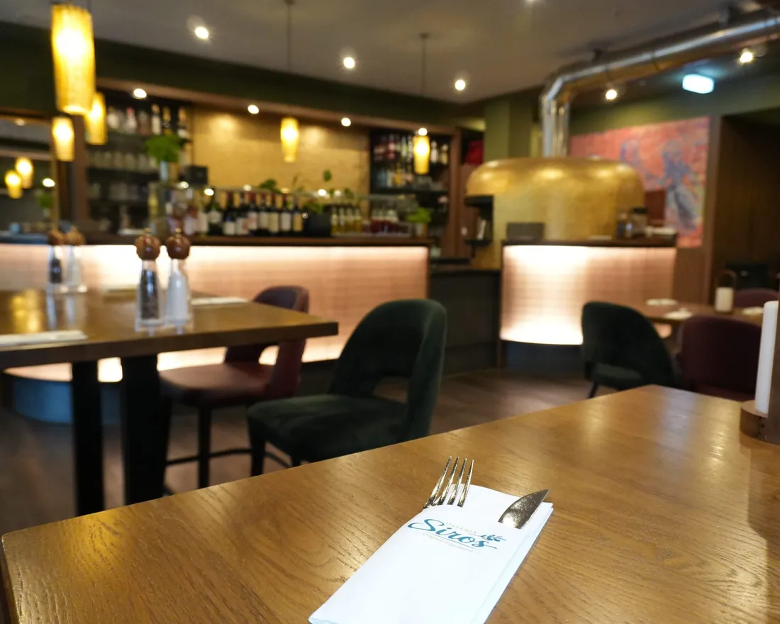 Gedeckte Tische mit Blick zur Bar der Osteria Siros
