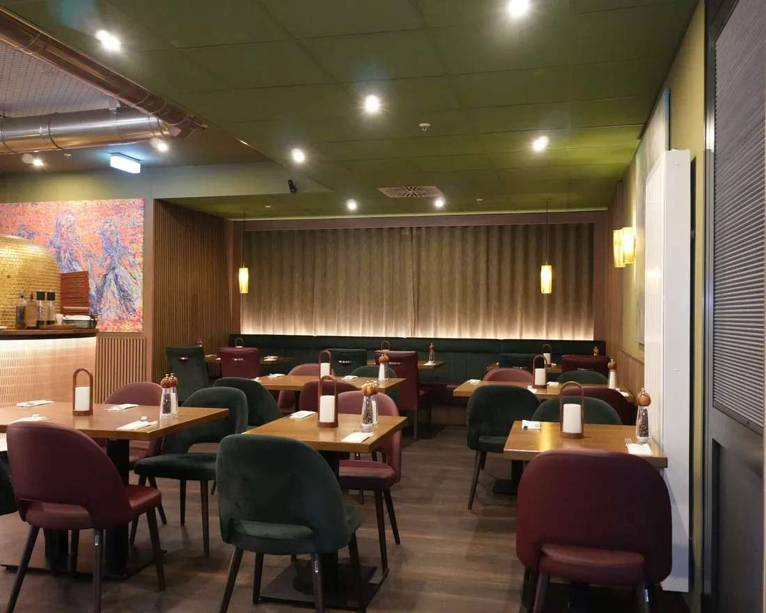 Der warme Gastraum der Osteria Siros mit sichtbarem Pizzaofen